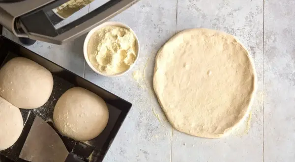 Förberedelser för pizza: poolish pizzadeg, mjöl i skål och degbollar i form.