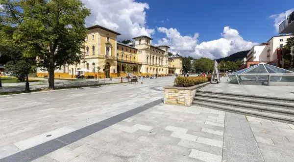 Piękny, słoneczny dzień w uzdrowisku. Ludzie spacerują po placu przed zabytkowym budynkiem. Zastanawiasz się, jak sprawdzić kolejkę do sanatorium?