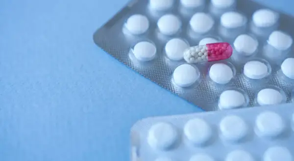 Dwie blistry z białymi tabletkami i jedna kapsułka z różowym i białym wypełnieniem. Zastanawiasz się, pulnozin na co?
