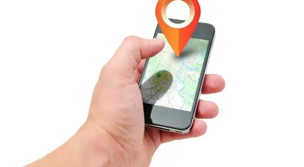 Dłoń trzyma smartfon z mapą i ikoną lokalizacji. Aplikacja pokazuje, jak działa lokalizator, gdzie jest dziecko.