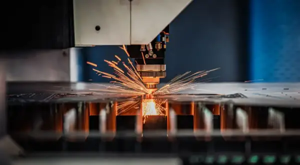 Precyzyjna obsługa maszyn CNC: laser tnie metal, sypią się iskry.