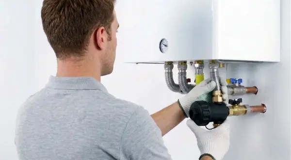 Tecnico installa componente su caldaia, assicurando la garanzia condizionatori.