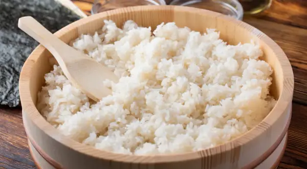 Gotowany ryż do sushi w drewnianym naczyniu z drewnianą łyżką.