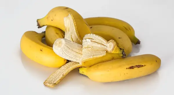 Kupa żółtych bananów, jeden częściowo obrany. Czy banan jest lekkostrawny? Tak, to świetna przekąska.
