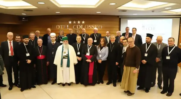 Grupa duchownych i świeckich, w tym muzułmanin w białej szacie, dyskutuje o albania religia.