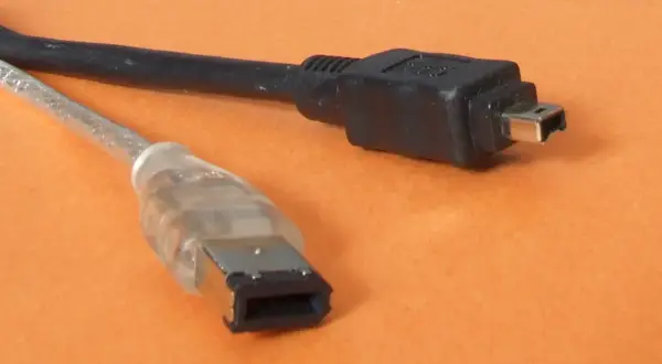 Dwa kable: jeden przezroczysty z szeroką wtyczką, drugi czarny z małą wtyczką. To złącza FireWire IEEE 1394.