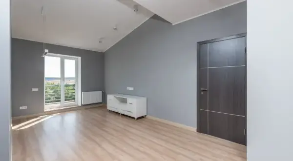 Nowe mieszkanie TBS z jasnym drewnianym parkietem, szarymi ścianami, białym meblem i drzwiami.