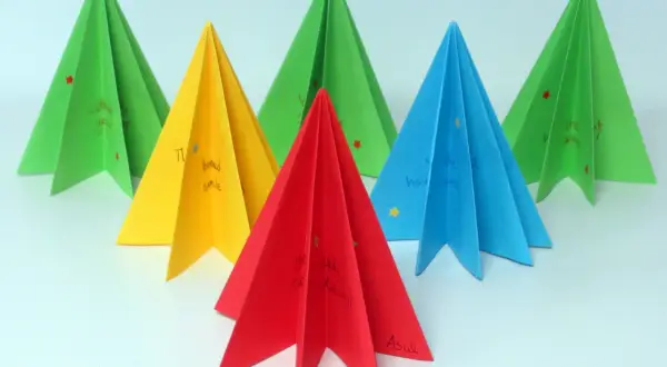 Kolorowe choinki origami płaskie z życzeniami. Zielone, żółte, czerwone i niebieskie ozdoby świąteczne.