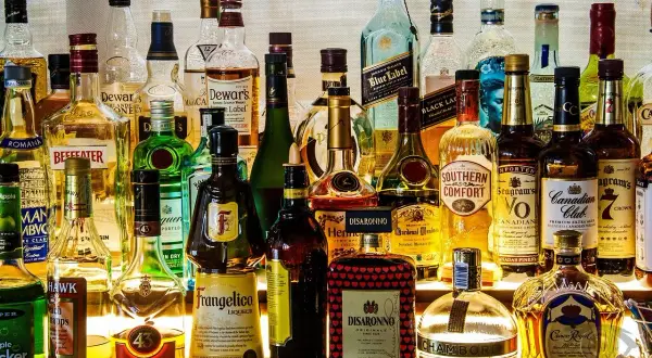 Różnorodne rodzaje alkoholi: whisky, likiery, gin, brandy i inne, stojące na półce.