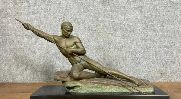 Sculpture d'un athlète en mouvement, tenant une lance. L'œuvre en bronze ou régule, est posée sur un socle en marbre noir.