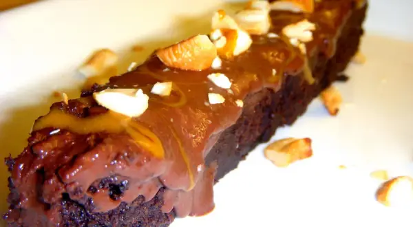 En bit fransk chokladtårta med chokladglasyr och nötter.