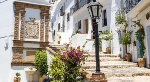 Escaleras empedradas y casas blancas adornadas con flores, un escudo de armas y una farola. Descubre qué ver en Frigiliana, un pueblo blanco andaluz.
