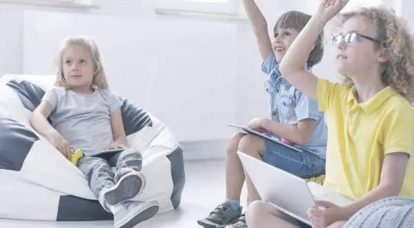 Niños participando en juegos en inglés para niños, levantando las manos con entusiasmo.