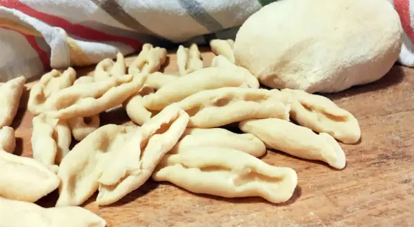 Strascinati pugliesi freschi, pronti per essere cucinati, su un tagliere di legno.