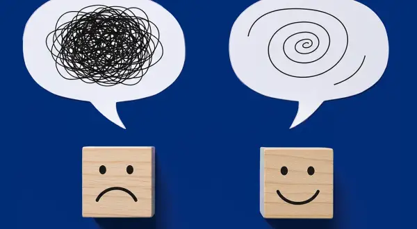 Dwa dymki: jeden z chaotyczną linią, drugi ze spiralą. Pod nimi kostki: smutna i uśmiechnięta. Symbolizują choroby psychosomatyczne i drogę do zdrowia.