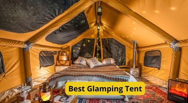 Wnętrze luksusowego namiotu glampingowego z wygodnym łóżkiem, piecykiem i nastrojowym oświetleniem. To jest właśnie glamping co to znaczy – komfort na łonie natury.