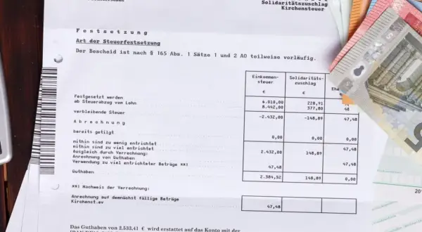 Steuerbescheid mit Geldscheinen. Eine Ratenzahlung ans Finanzamt ist hier nicht direkt ersichtlich, aber das Thema Steuern ist präsent.