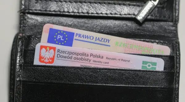 Czarny portfel z polskim dowodem osobistym i prawem jazdy. Na dokumencie prawa jazdy widnieje napis "PRAWO JAZDY" oraz symbol Unii Europejskiej.