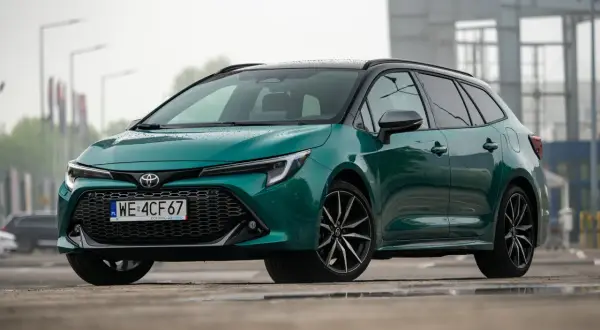 Zielona Toyota Corolla Touring Sports hybrid na mokrej nawierzchni.