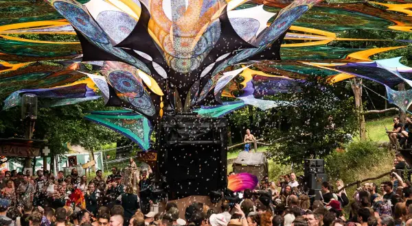 Bunte Stoffbahnen überspannen die Menge auf dem Wunderland Festival. Seifenblasen steigen auf, während die Besucher tanzen.