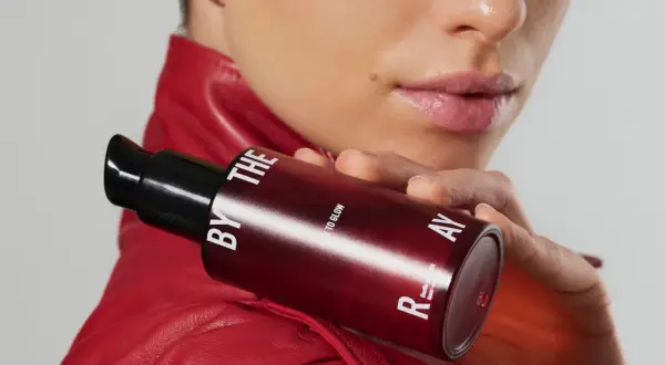 Kobieta w czerwonej ramonesce trzyma buteleczkę z serum. Czy to kwasy PHA jakie to? Delikatne dla skóry, dla blasku.