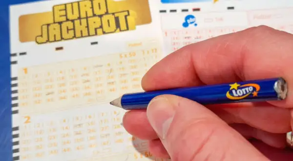 Dłoń z ołówkiem Lotto na kuponie Eurojackpot. Zastanawiasz się, dlaczego los w Eurojackpot w Polsce jest droższy?