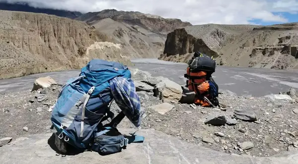 Plecak czeka na dalszą drogę. W tle majestatyczne góry i rzeka, idealne miejsce na trekking w Himalajach.