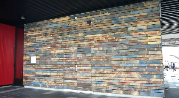 Un mur en palette extérieure aux couleurs vives et variées, créant une texture unique.