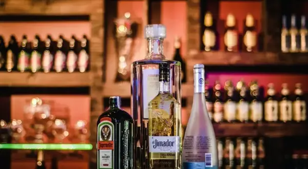 Butelka Jägermeistera, z etykietą informującą o zawartości alkoholu, stoi obok innych alkoholi.