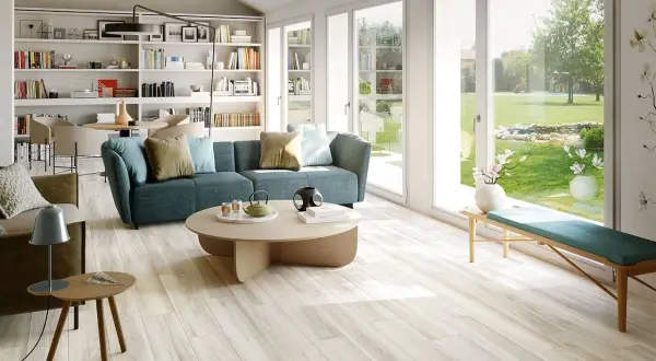Soggiorno luminoso con divano blu e pavimento in gres porcellanato effetto legno, che mostra come rendere lucido il gres porcellanato effetto legno.