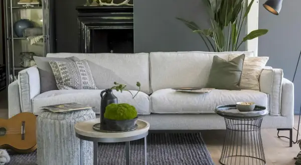 Ein hellgraues Sofa mit verschiedenen Kissen. Die Frage, welche Sofa-Polsterung die beste ist, wird hier stilvoll beantwortet.