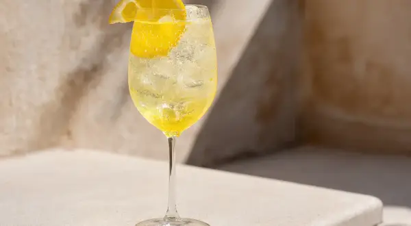 Ett glas med is och en bubblig limoncello drink, garnerad med en citronskiva.