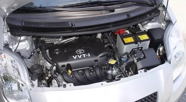 Silnik Toyoty Yaris II z widocznym akumulatorem i elementami osprzętu.