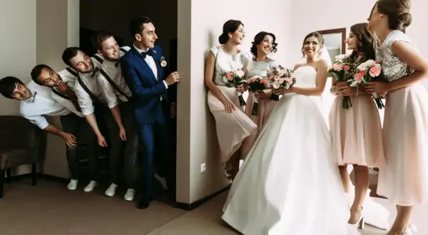 Bräutigam und Trauzeugen stehen Spalier, während die Brautjungfern mit Blumensträußen auf die Braut warten. Eine lustige Szene, die die **Trauzeugen Pflicht** humorvoll darstellt.