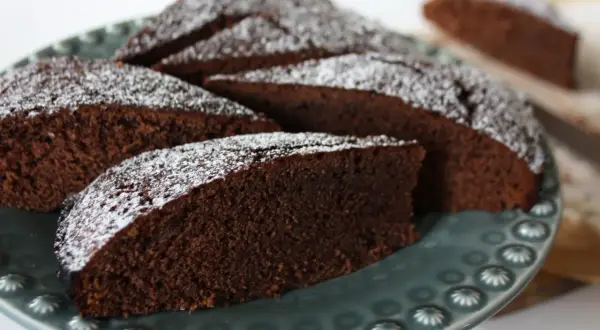 Skivor av saftig chokladkaka med kakao, pudrade med florsocker, ligger på en vacker gråblå tallrik.