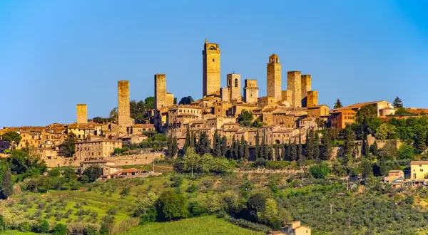 San Gimignano z wieżami, otoczone zielonymi wzgórzami Toskanii, gdzie dojrzewają winogrona na wino Vernaccia di San Gimignano.