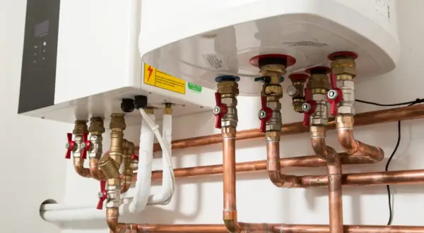 Instalacja grzewcza z pompą ciepła. Widoczne miedziane rury, zawory i przyłącza do istniejącej instalacji.