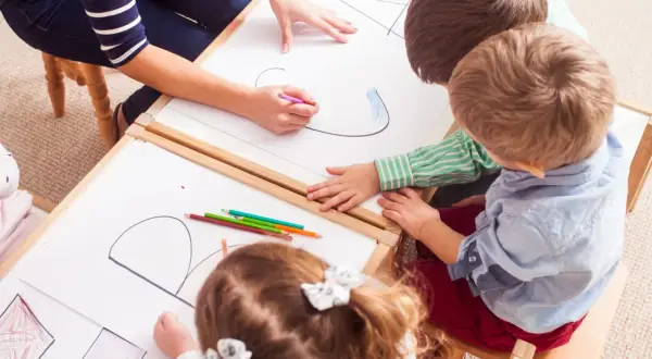 Kinder malen und lernen spielerisch im Kindergarten. Bunte Stifte und viel Kreativität bei den Sprachspielen.