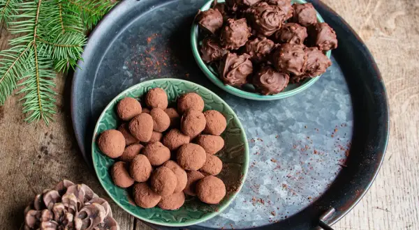 Deux assiettes de truffes au chocolat, certaines enrobées de cacao, d'autres de chocolat fondu. Parfait pour une recette des truffes au chocolat festive.