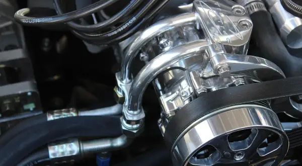 Detalle de un motor con piezas cromadas brillantes y cables. Se escucha un leve traqueteo en el motor, quizás por la tensión de la correa.