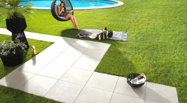 Posa di un pavimento in gres porcellanato con uno spessore ideale per esterni, che crea un'area relax con piscina e vista mare.