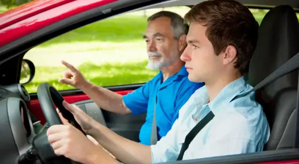 Joven conductor aprende a manejar con su instructor. ¡Con 17 años ya se puede sacar el carnet de conducir!
