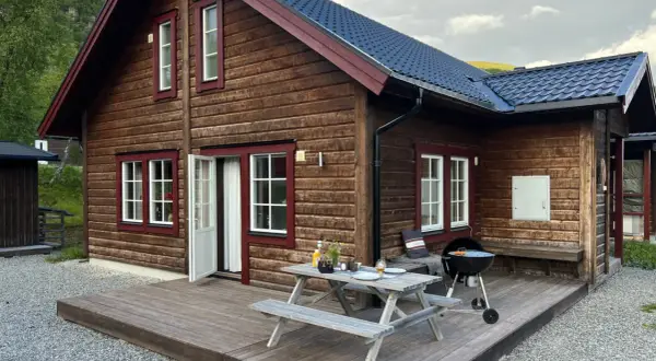 Mysig trästuga med grill och picknickbord på altanen, perfekt för en avkopplande vistelse på buskvallen inn.