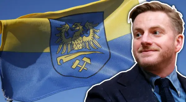 Szczepan Twardoch na tle flagi z godłem Górnego Śląska.