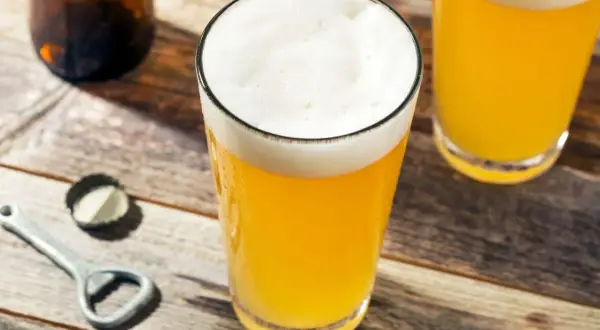Bicchieri di birra dorata con schiuma bianca, su un tavolo di legno. La gradazione alcolica della birra è un dettaglio importante per gli amanti.