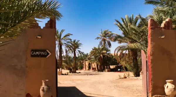 Ein Tor führt zu einem Campingplatz in Marokko, umgeben von Palmen. Ja, ist Marokko sicher für Reisende.