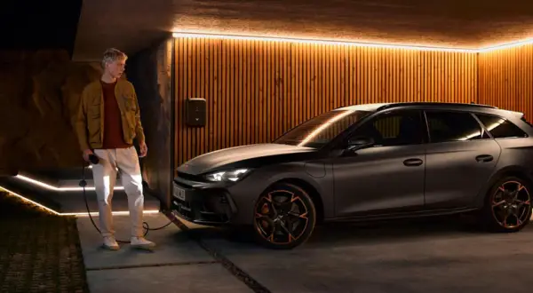 Man laddar en mörk kombi, en phev betyder att den kan köras på både el och bensin.