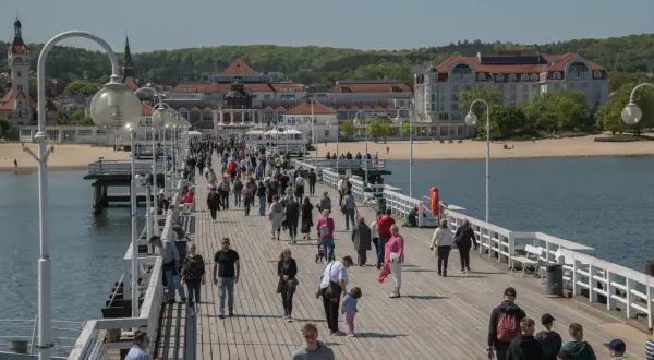 Spacer po molo w Sopocie, gdzie tłumy ludzi korzystają z pięknej pogody. To świetne miejsce na relaks i odkrywanie **Gdańsk atrakcje dla młodzieży**.