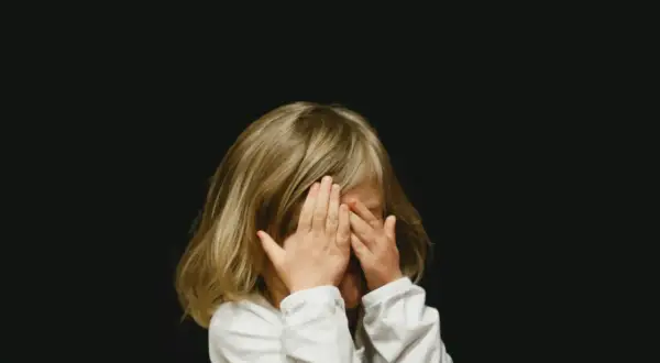 Dziecko zakrywa oczy dłońmi. Szukamy sposobów na rozładowanie emocji u dzieci, by mogły swobodnie wyrażać siebie.