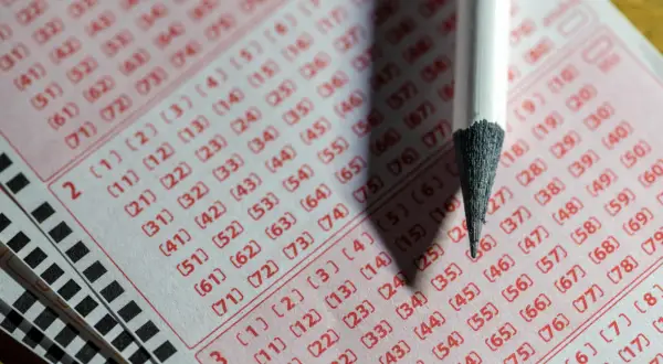 Zbliżenie na kupon lotto z zaznaczonymi liczbami i ołówkiem.